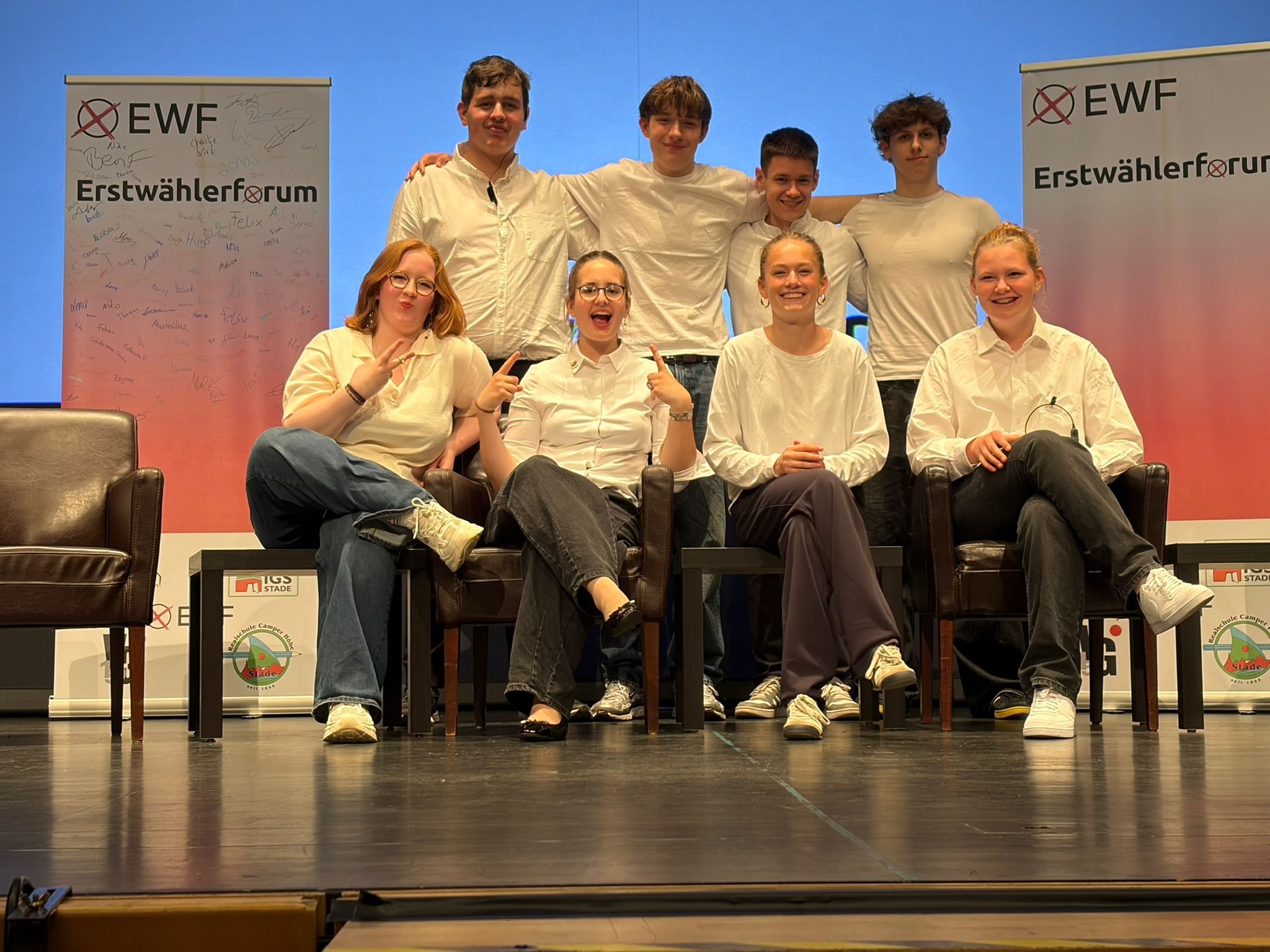 Gruppenfoto des Leitungsteams auf einer Bühne vor Bannern des Erstwählerforums