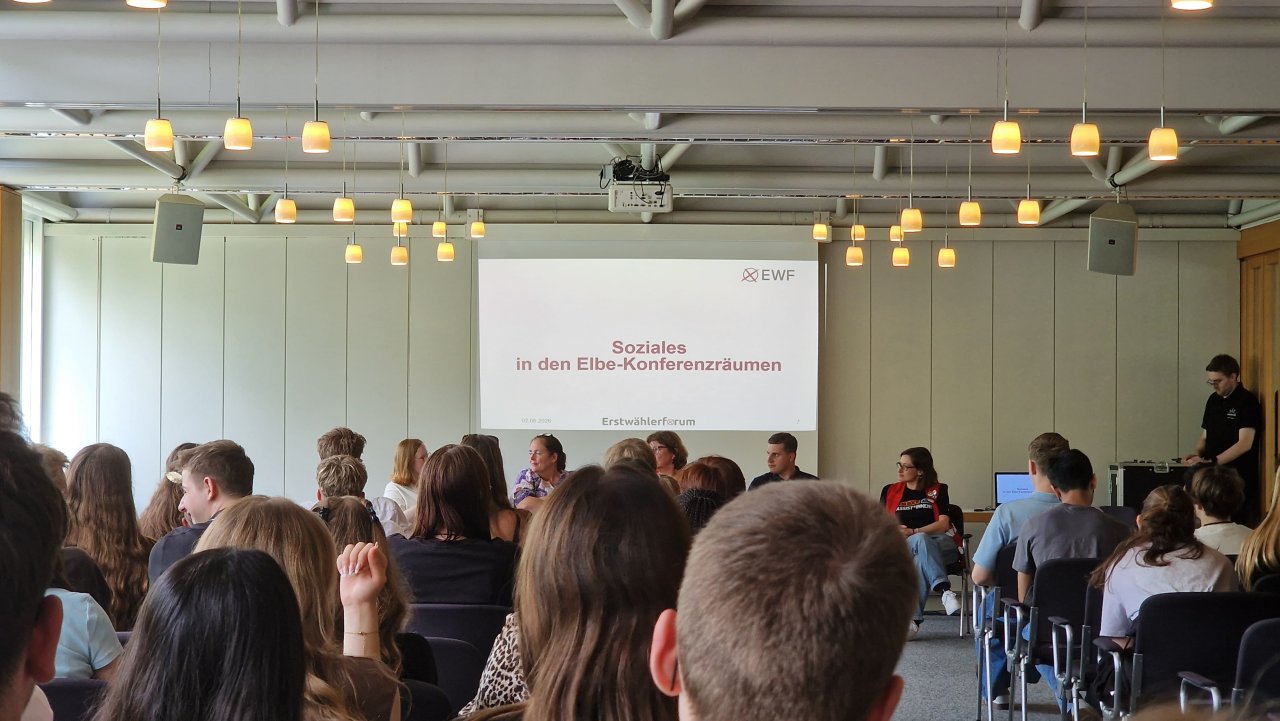 Gesprächsrunde vor einer Präsentation über Schule im Veranstaltungsraum.
