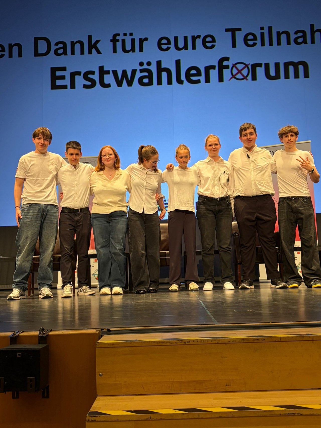 Gruppe vor der Abschlussfolie des Erstwählerforums, vom Bühnenrand fotografiert.