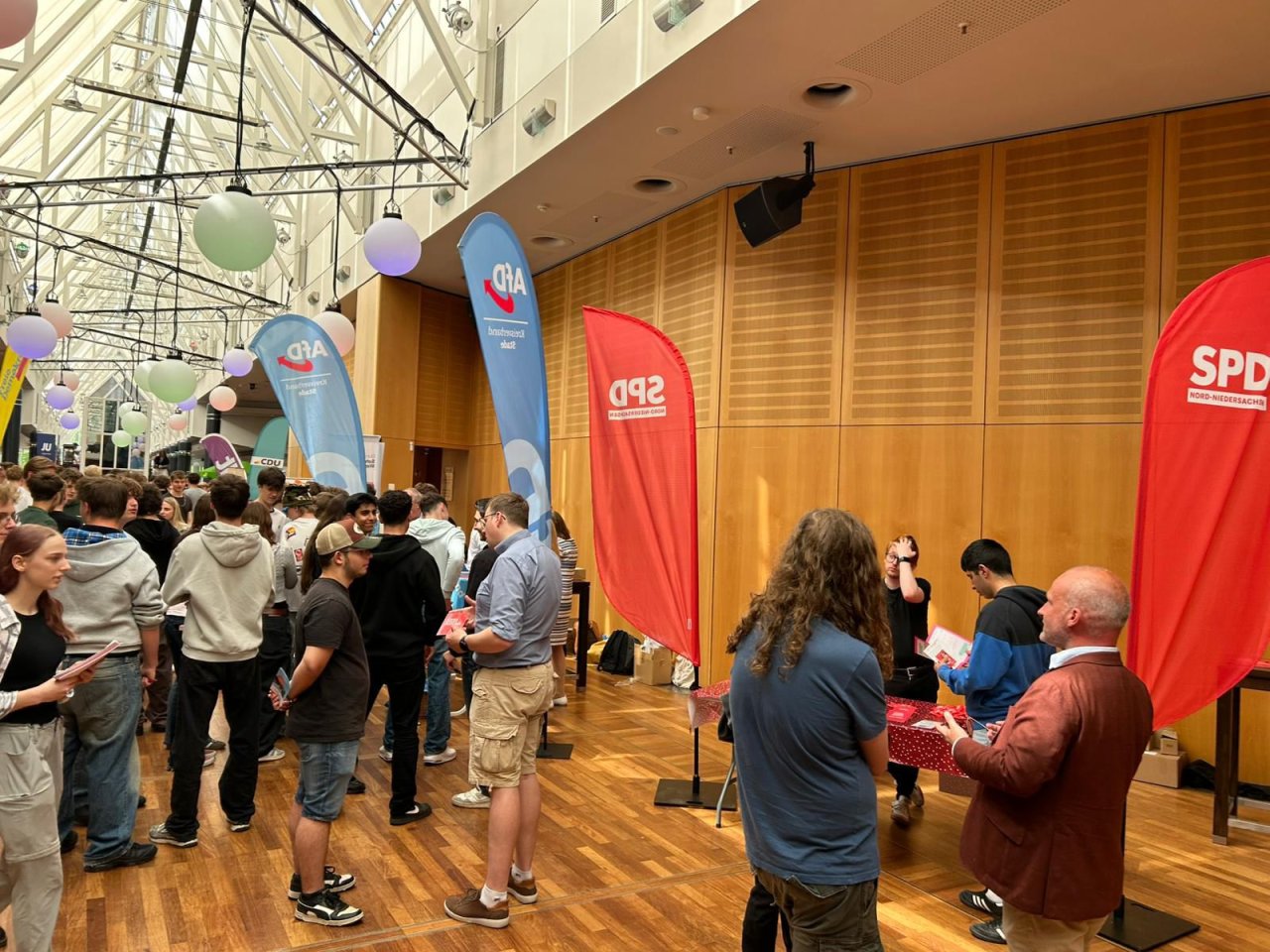 Gespräche an Informationsständen im Foyer, rechts ein SPD-Banner.
