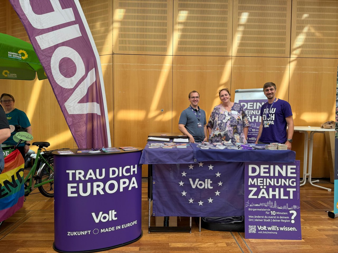 Drei Personen hinter einem Volt-Informationsstand im Foyer.